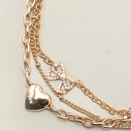 Multi-layer gold charm bracelet with heart charm and pearl bow on chain links, 7.5” with 2” extender