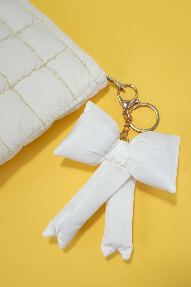 White bow keychain on a yellow background