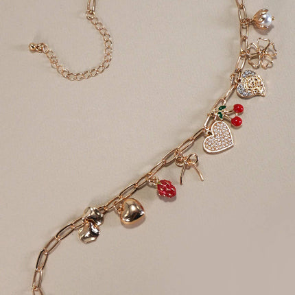 Gold chain necklace with various charms on a beige background