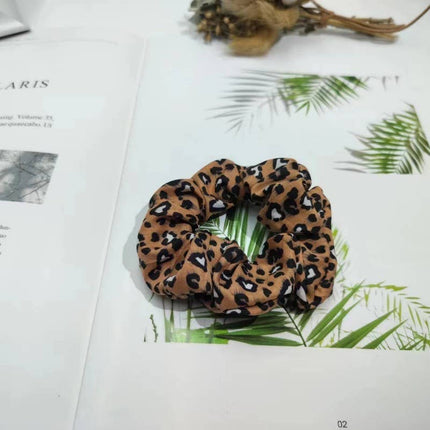 Leopard print scrunchie on a magazine with green leaves