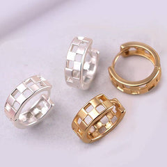 Four hoop earrings in gold and silver on a light purple background