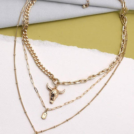 Gold plated three layer western style necklace featuring polished bull horn charm with elongated link chains and adjustable lobster claw clasp displayed on a feminine styled background.