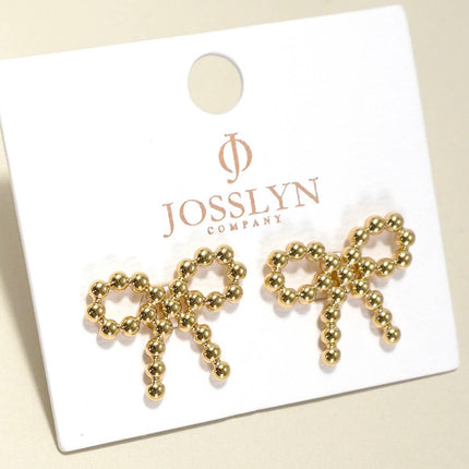 Gold bow-shaped earrings on a JOSSLYN Company card.