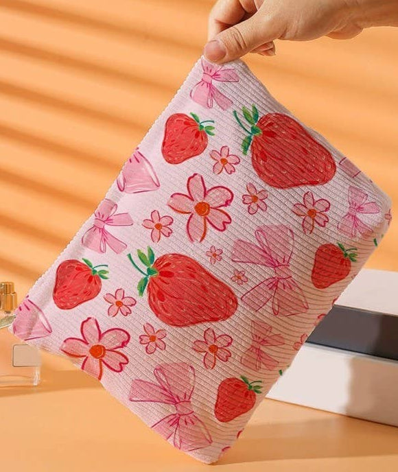 Hand holding a pink towel with strawberry pattern against an orange background