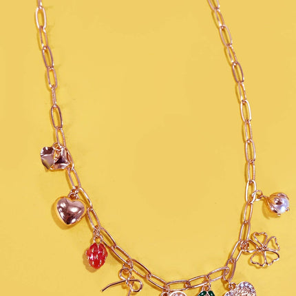 Gold necklace with various charms on a yellow background
