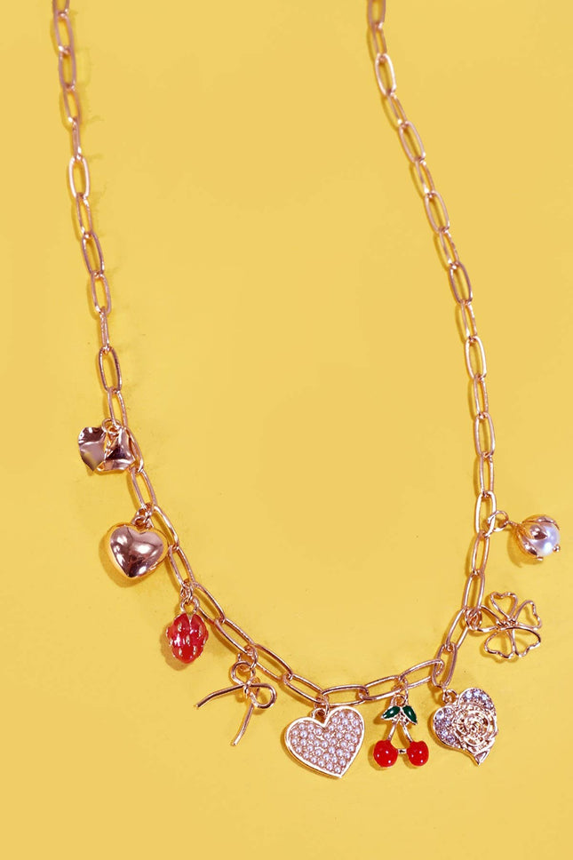 Gold necklace with various charms on a yellow background