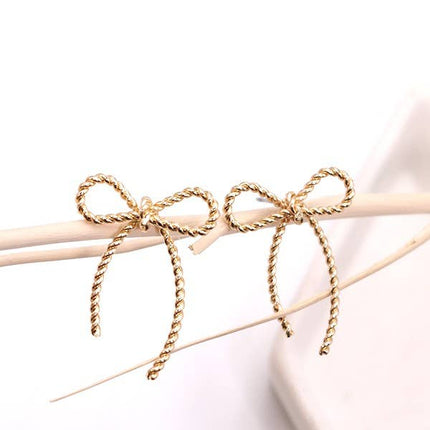 Gold bow-shaped earrings on a white background
