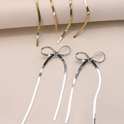 Gold and silver hair accessories with bow designs on a pink and beige background