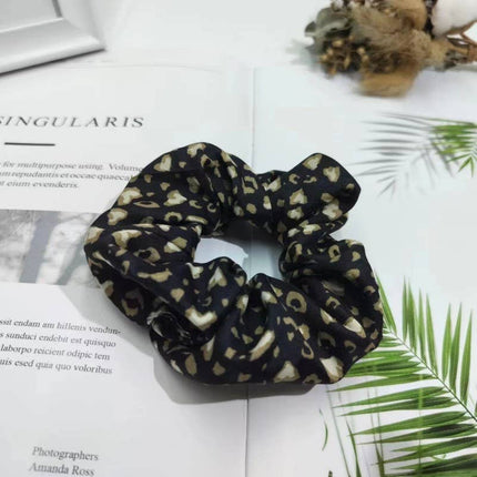 Leopard print scrunchie on a magazine with text and green leaves.