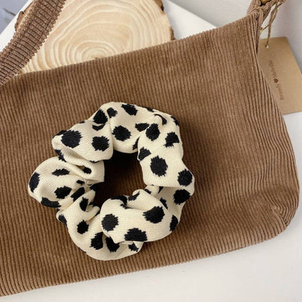 Black and white polka dot scrunchie on a brown textured surface