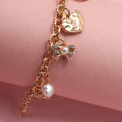 Gold-plated charm bracelet with bow, heart, pearl, and textured disc charms, 6.5” with 2” adjustable extender