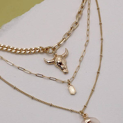 Gold plated three layer western style necklace featuring polished bull horn charm with elongated link chains and adjustable lobster claw clasp displayed on a feminine styled background.