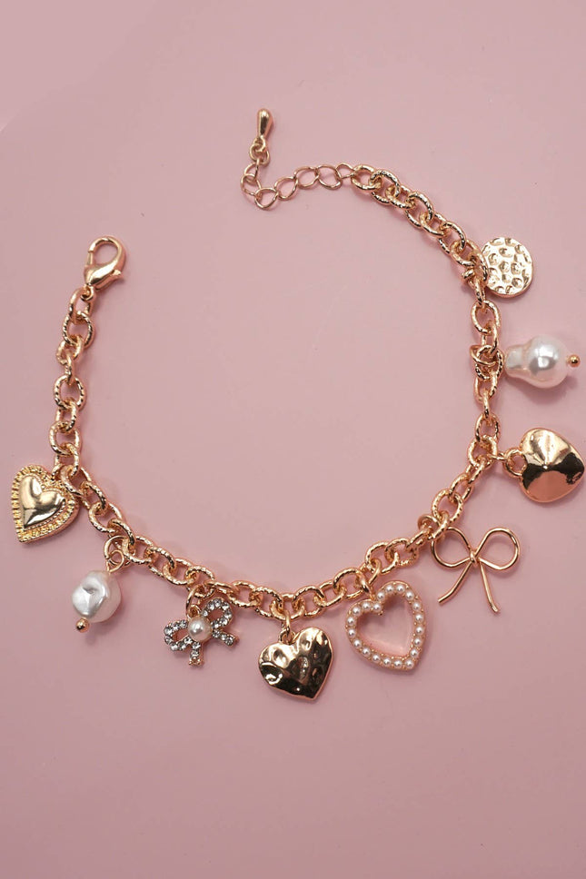 Gold-plated charm bracelet with bow, heart, pearl, and textured disc charms, 6.5” with 2” adjustable extender