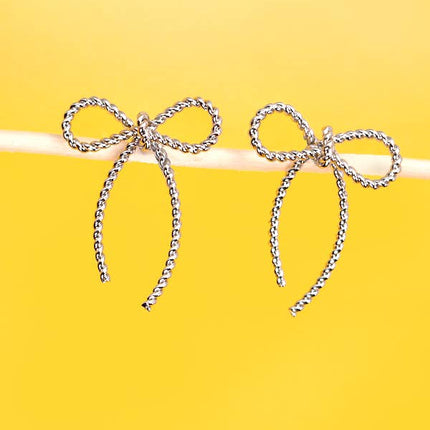 Bow-shaped earrings on a yellow background