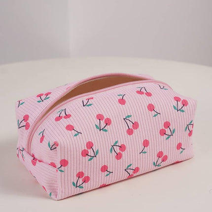 Pink costmetic bag with cherry pattern on a white surface
