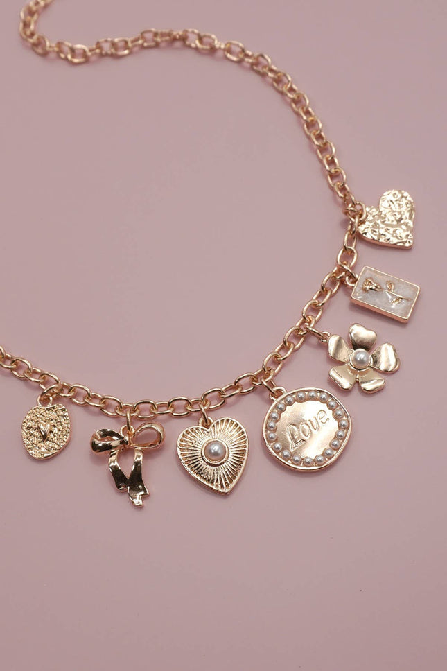Rose gold charm bracelet on a pink background