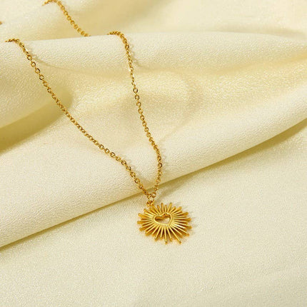 Gold necklace with a sunflower pendant on a beige fabric background