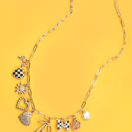 Gold necklace with various charms on a yellow background