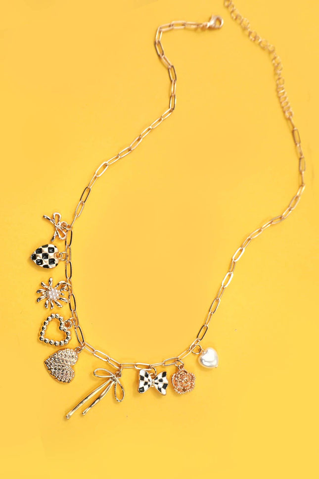 Gold necklace with various charms on a yellow background