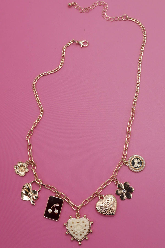 Gold charm necklace featuring bow, heart, cherry, and floral pendants on a link chain with extender clasp.