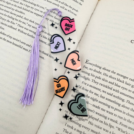 Handmade acrylic Valentine’s Day bookmarks featuring pink and red heart-themed designs with tassels, styled on open books for a cozy, festive reading aesthetic.