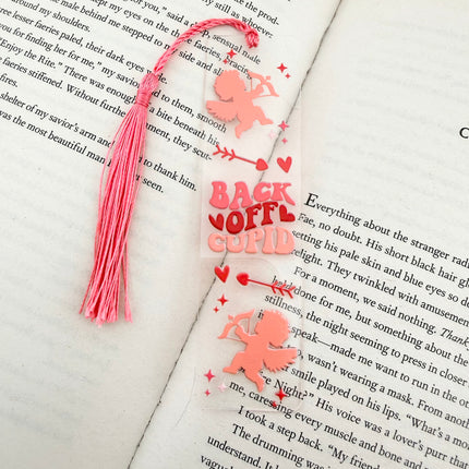 Handmade acrylic Valentine’s Day bookmarks featuring pink and red heart-themed designs with tassels, styled on open books for a cozy, festive reading aesthetic.