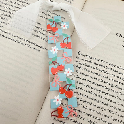 Clear acrylic Valentine’s Day bookmarks with pastel designs and soft chiffon ribbons resting inside open books, styled with a cozy, romantic bookish aesthetic.