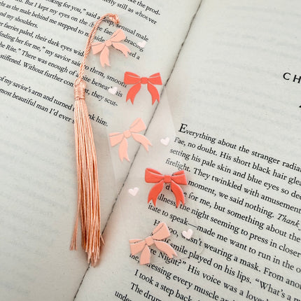Handmade acrylic Valentine’s Day bookmarks featuring pink and red heart-themed designs with tassels, styled on open books for a cozy, festive reading aesthetic.