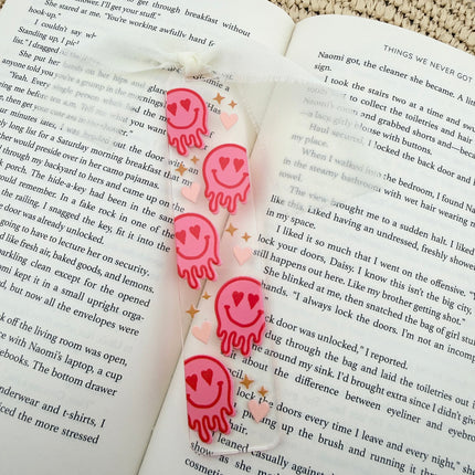 Clear acrylic Valentine’s Day bookmarks with pastel designs and soft chiffon ribbons resting inside open books, styled with a cozy, romantic bookish aesthetic.