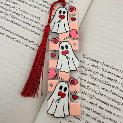 Handmade acrylic Valentine’s Day bookmarks featuring pink and red heart-themed designs with tassels, styled on open books for a cozy, festive reading aesthetic.