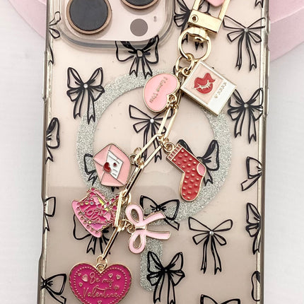 Phone case with bow designs and charms on a light pink background