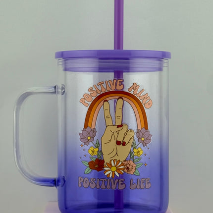 Purple tumbler with a handle and straw featuring a hand and flowers design on a light gray background