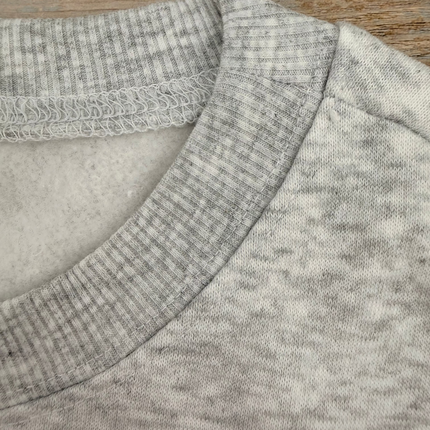 Light grey sweatshirt with pink bow graphic on chest, relaxed fit, drop shoulders, and ribbed hem and cuffs.