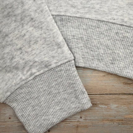 Light grey sweatshirt with pink bow graphic on chest, relaxed fit, drop shoulders, and ribbed hem and cuffs.