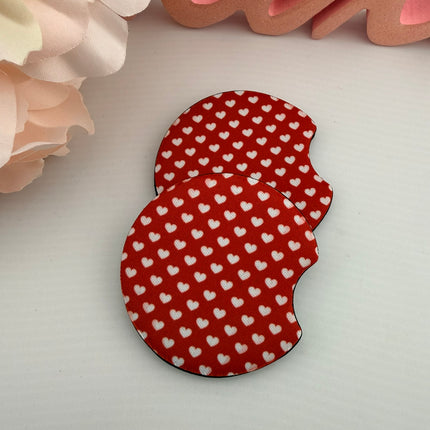 Two Valentine’s Day–themed neoprene car coasters with heart and love patterns, shown inside gift-ready packaging and styled on a neutral background.