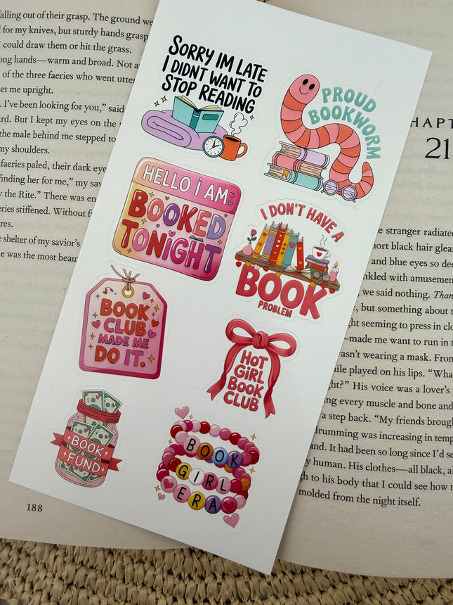 Multiple book lover sticker sheet designs featuring cozy reading themes, spicy book humor, hearts, books, and playful illustrations displayed on an open book background.