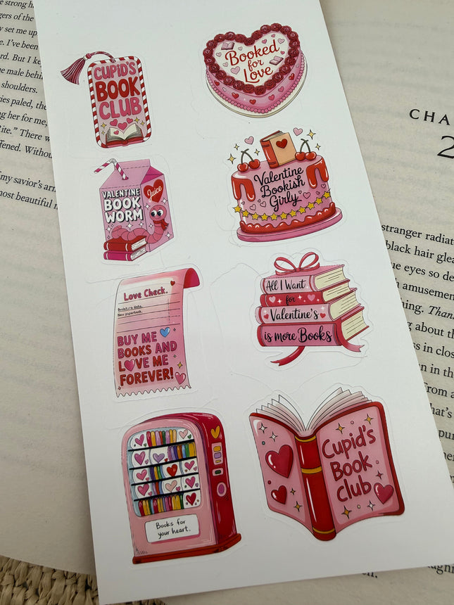 Valentine’s-themed bookish sticker sheets featuring pink and red hearts, books, cakes, and reading-inspired designs styled on an open book.