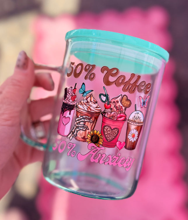 Glass tumbler with colorful coffee-themed design and text, held by a hand against a pink background.
