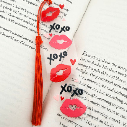 Handmade acrylic Valentine’s Day bookmarks featuring pink and red heart-themed designs with tassels, styled on open books for a cozy, festive reading aesthetic.