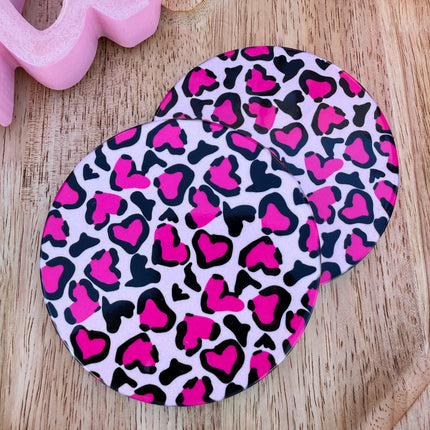 Round ceramic Valentine coasters featuring pink and red heart, bow, and XOXO designs, styled on a neutral surface and packaged ready to gift.