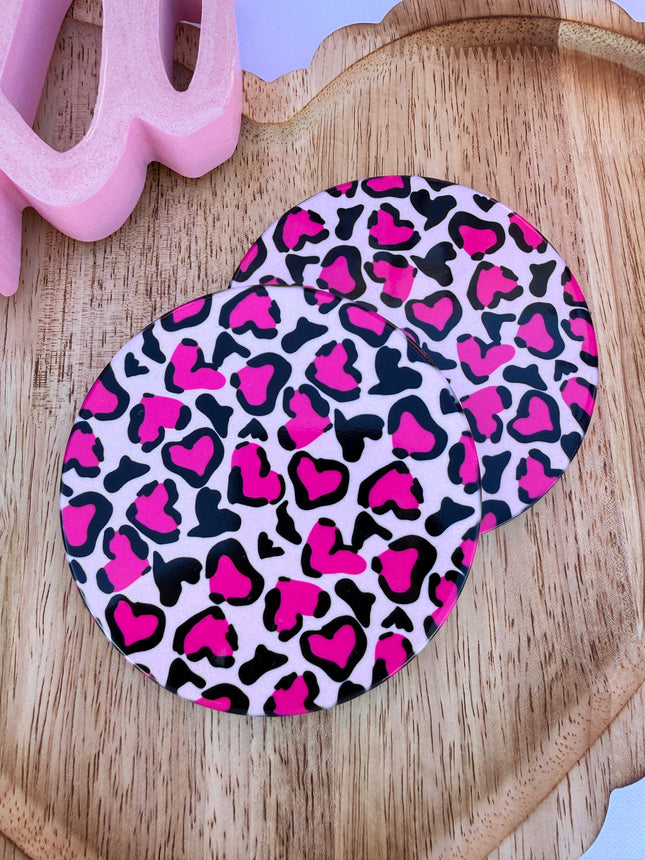 Round ceramic Valentine coasters featuring pink and red heart, bow, and XOXO designs, styled on a neutral surface and packaged ready to gift.