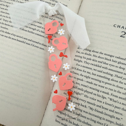 Clear acrylic Valentine’s Day bookmarks with pastel designs and soft chiffon ribbons resting inside open books, styled with a cozy, romantic bookish aesthetic.