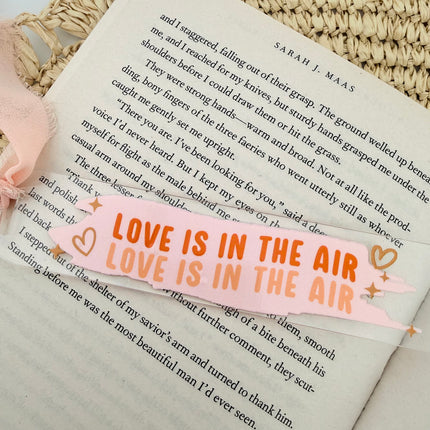 Clear acrylic Valentine’s Day bookmarks with pastel designs and soft chiffon ribbons resting inside open books, styled with a cozy, romantic bookish aesthetic.