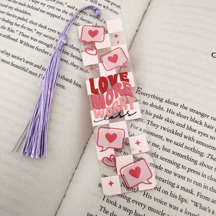 Handmade acrylic Valentine’s Day bookmarks featuring pink and red heart-themed designs with tassels, styled on open books for a cozy, festive reading aesthetic.