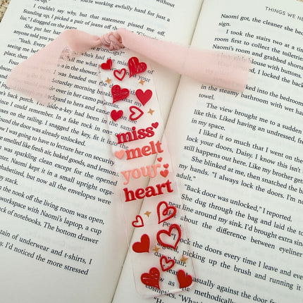 Clear acrylic Valentine’s Day bookmarks with pastel designs and soft chiffon ribbons resting inside open books, styled with a cozy, romantic bookish aesthetic.