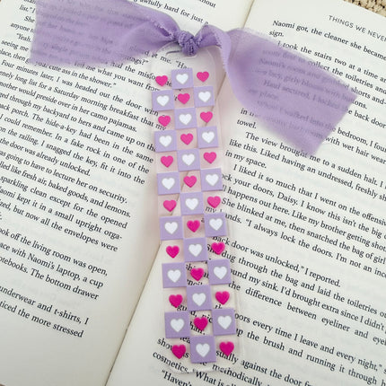 Clear acrylic Valentine’s Day bookmarks with pastel designs and soft chiffon ribbons resting inside open books, styled with a cozy, romantic bookish aesthetic.