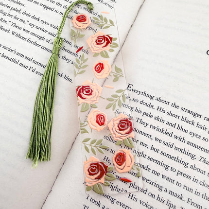 Handmade acrylic Valentine’s Day bookmarks featuring pink and red heart-themed designs with tassels, styled on open books for a cozy, festive reading aesthetic.