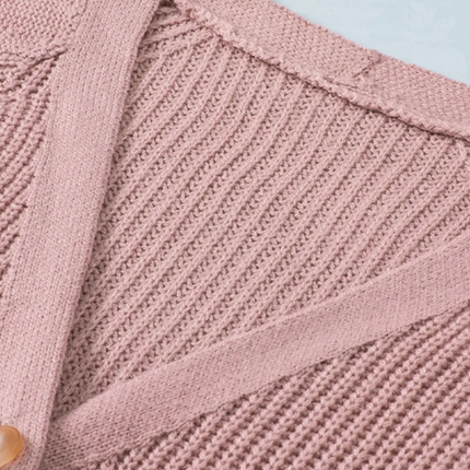 Close-up of a pink knitted cardigan with a button on a light blue background