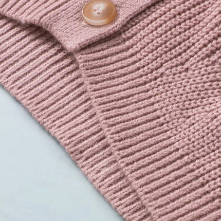 Close-up of a pink knitted garment with a button on a light blue background