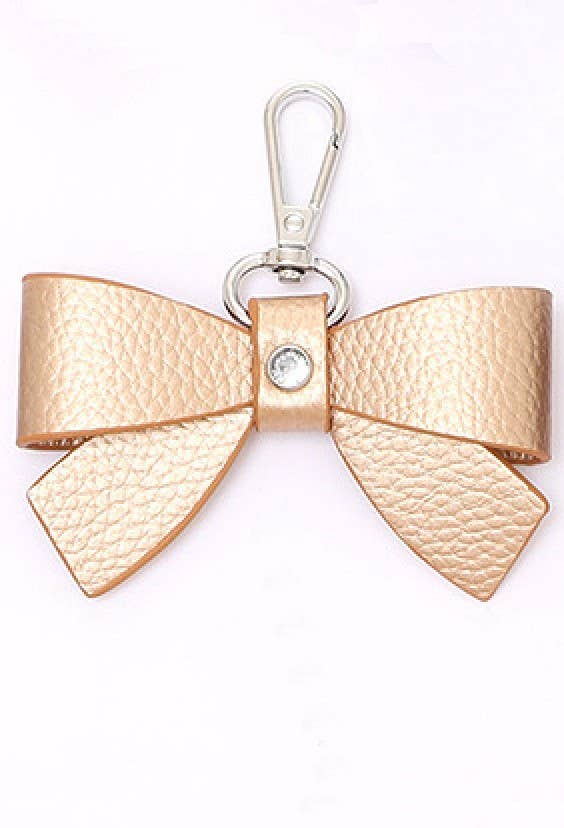 Gold bow-shaped keychain with a clear gemstone on a white background